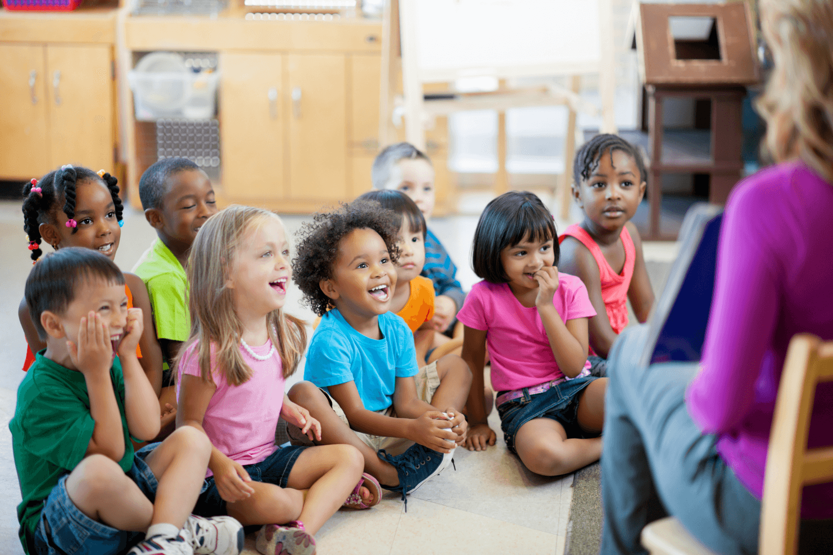Teacher reading to children during circle time in a bright classroom.